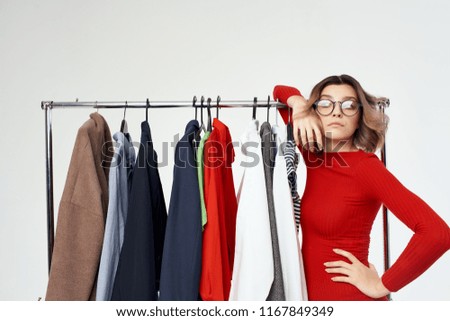 the woman in glasses leaned on the iron base of the wardrobe with clothes                             
