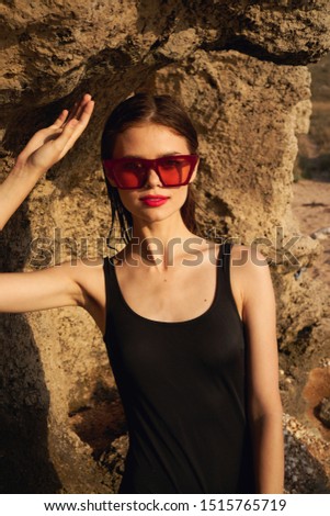 woman with glasses near the ocean in a black swimsuit