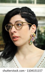 Woman With Glasses And Undercut Hairstyle Wearing Colorful Statement Earrings.