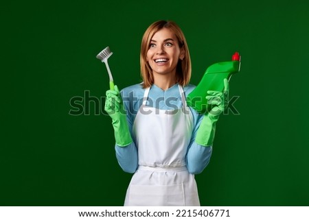 woman in gloves holding brush and bottle of detergent