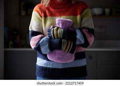 Woman In Gloves Hugging Hot Water Bottle Trying To Keep Warm During Cost Of Living Energy Crisis