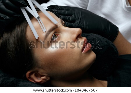 Woman in gloves making measuring of eyebrows before permanent powder staining
