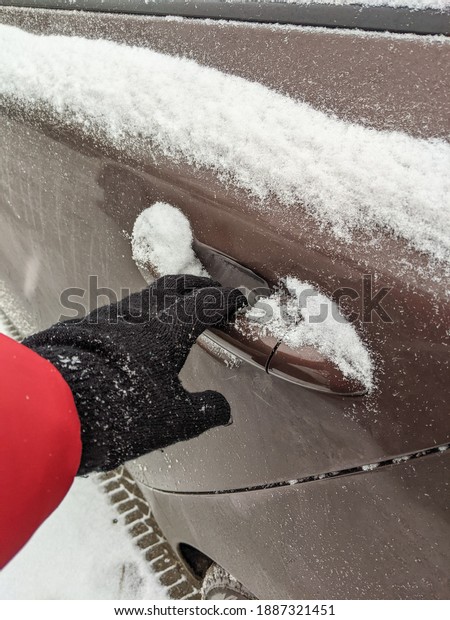 woman in gloves opens the car door covered with\
snow. snowy winter. hand\
close-up