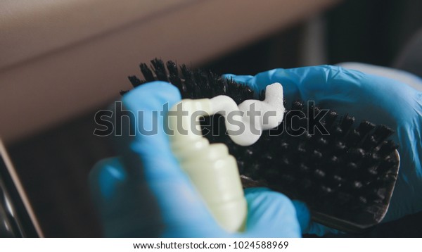Woman in gloves is puting cream on the brush and\
washing a car interior