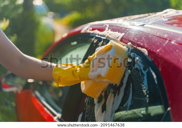 Woman in gloves\
washes car windows with\
sponge.