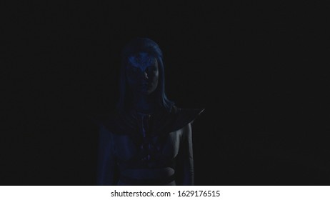Woman with a glowing blue face looks at the camera when the light blinks 