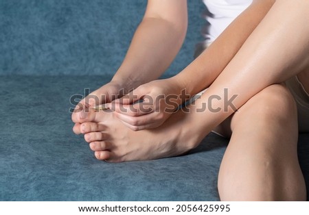 A woman glues a plaster for the treatment of calluses and calluses to her toe.