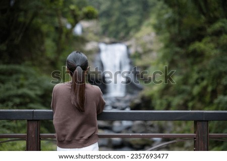 Woman go hiking and look at the waterfall in forest