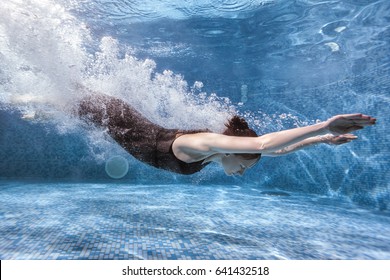 Woman goes in for sports in the pool, she dives underwater.