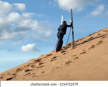 Woman Goes Uphill Of Dune With Skis In Her Hand. Sand-skiing Is Sport And Form Of Skiing In Which Skier Rides Down Sand Dune On Skis, Using Ski Poles. Tver, Russia - 2006