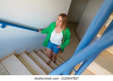 Woman Going Up The Stairs In Apartment House.