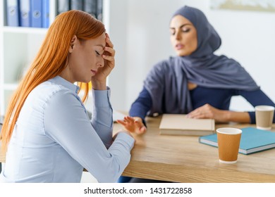 Woman Going Through A Tough Time. Her Muslim Co-worker Touches Her Hands And Give Emotional Help. Supportive Work Environment In The Office.