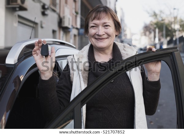 woman in\
golden age standing with car key\
outdoor