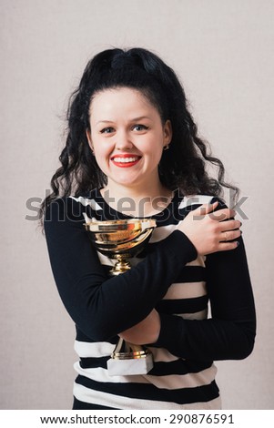 A woman with a golden cup victory. Gray background.