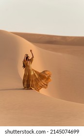 Woman With Golden Dress Dancing On The Sand Dunes