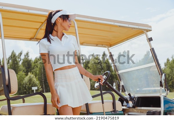 Woman\
golf car driver in white uniform, stand at club\
car