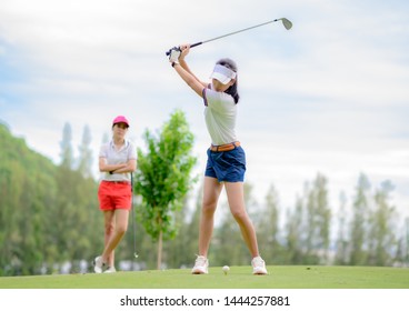 woman golf player in action being setup address of back swing to hit the golf ball away from T-OFF to the destination on the green, fairway at day light sky, PAR 3 T OFF