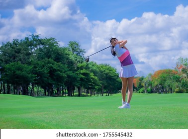 Woman golf player in action being setup address of back swing to hit the golf ball away from T-OFF to the destination on the green, fairway at day light sky.