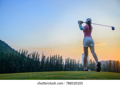 a woman golf player in an action at the ene of downswing, after hit the golf ball away from tee off to the fairway ahead by wood driver