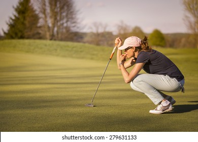 Woman golf player crouching and study the green before putting shot. - Powered by Shutterstock