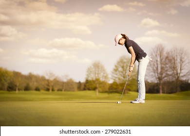 Woman golf player putting on green at dusk, with empty copyspace. - Powered by Shutterstock