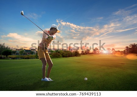 woman golf player try to hit the golf ball on nthe fairway of the golf course to the green at prospectation of best resulted, with sunrise in background