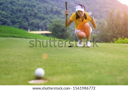 woman golfer in action of exciting of flowing of golf ball run almost to golf hole on the green