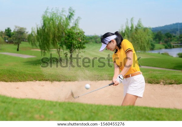 woman golfer hit sand ground exposure trying to\
approach or reach to hole final destination on the green, hit sand\
bunker attempt by woman\
golfer\
