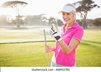 Woman golfer looking her mobile phone on field