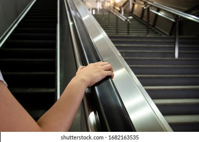 Woman grabbing the escalator hand rail while standing on the escalator, woman going down the stair in the shopping mall by using escalator. Safety awareness in everyday life concept.