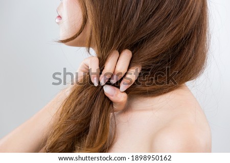 The woman is grabbing her damaged hair.