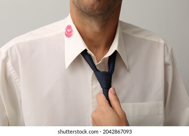Woman grabbing her husband by tie due lipstick kiss mark on his shirt, closeup