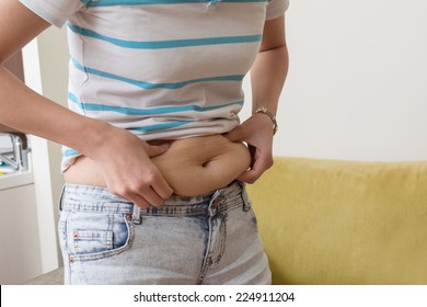 A Woman Is Grabbing A Love Handles Around Her Waist.