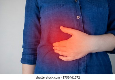 A woman grabs his right side under the ribs. Pain in the liver. Pain syndrome in liver disease. Hepatologist examination - Shutterstock ID 1758461372