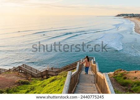 Woman gracefully descends the South Port Beach stairs captivated by the spectacular sea view during sunset, Port Noarlunga, South Australia