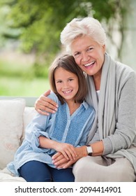 Woman And Granddaughter Smiling On Porch Swing