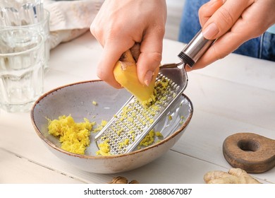 Woman grating ginger on white wooden background - Powered by Shutterstock