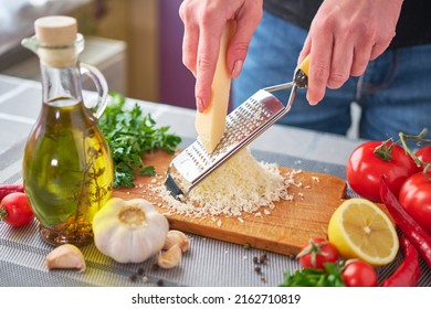 Woman grating parmesan cheese on a grater at domestic kitchen