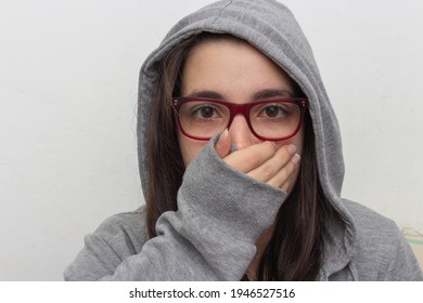 Woman In Gray Blouse On White Background Surprised With Hand Over Mouth