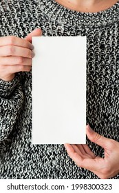 Woman in a gray sweater holding an earth tone card mockup