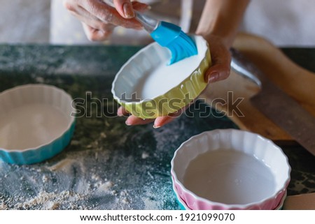 Woman greasing baking mould before adding batter.