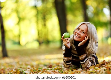 Woman With Green Apple In Autumn Park