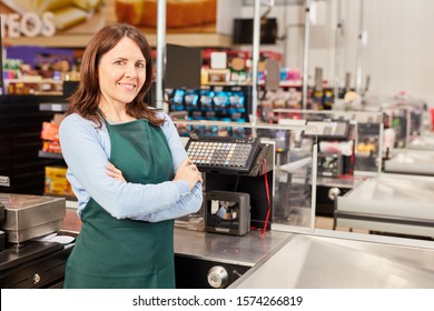 Woman in green apron as a cashier at the cash register in the supermarket or discounter