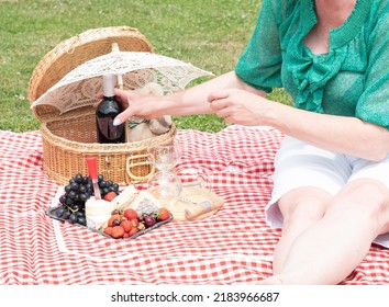 Woman In A Green Blouse Sits On A Red Checkered Picnic Rug, Red Wine And Chees