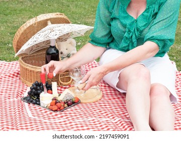 Woman In A Green Blouse Sits On A Red Checkered Picnic Rug, Red Wine And Chees