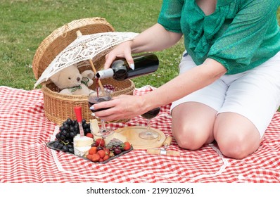 Woman In A Green Blouse Sits On A Red Checkered Picnic Rug, Red Wine And Chees