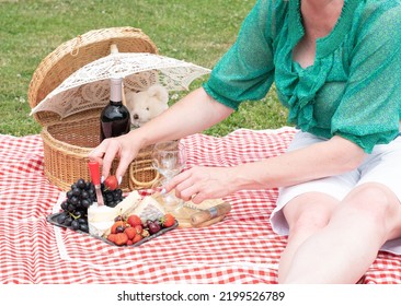 Woman In A Green Blouse Sits On A Red Checkered Picnic Rug, Red Wine And Chees