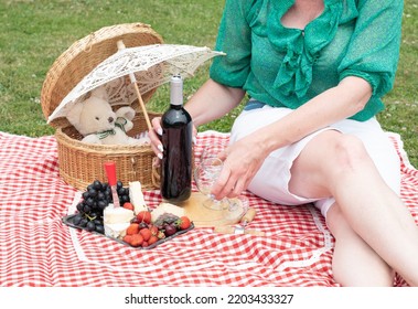 Woman In A Green Blouse Sits On A Red Checkered Picnic Rug, Red Wine And Chees