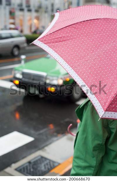 Woman in a green coat with pink umbrella in Aoyama,\
Tokyo, Japan