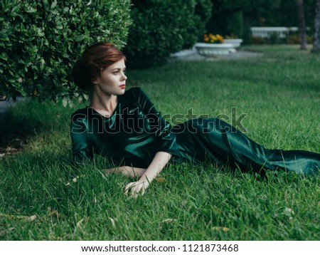 woman in a green dress lies on the grass